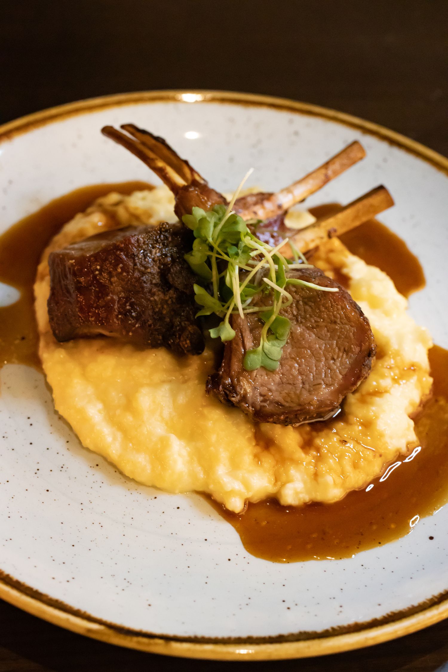 Half Rack of New Zealand Lamb chops on a plate with mashed potatoes and gravy at Lāk restaurant 