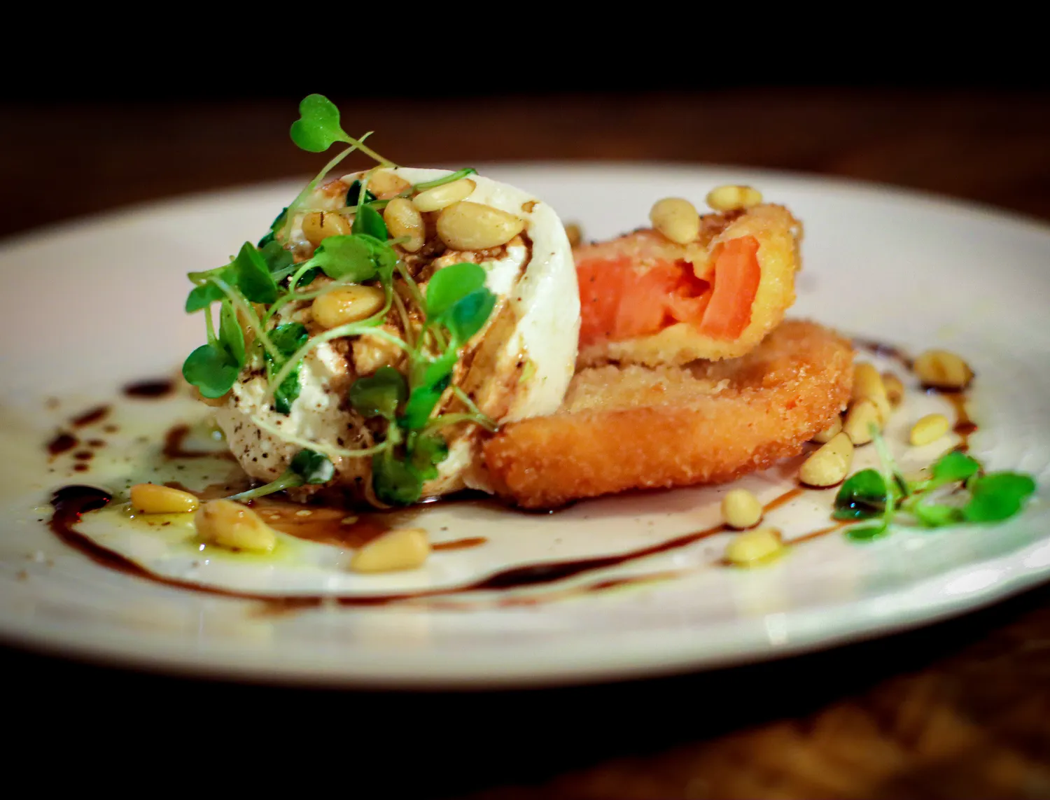 The delicious burrata appetizer at Earl's New American. Plated with pine nuts and fresh greens.