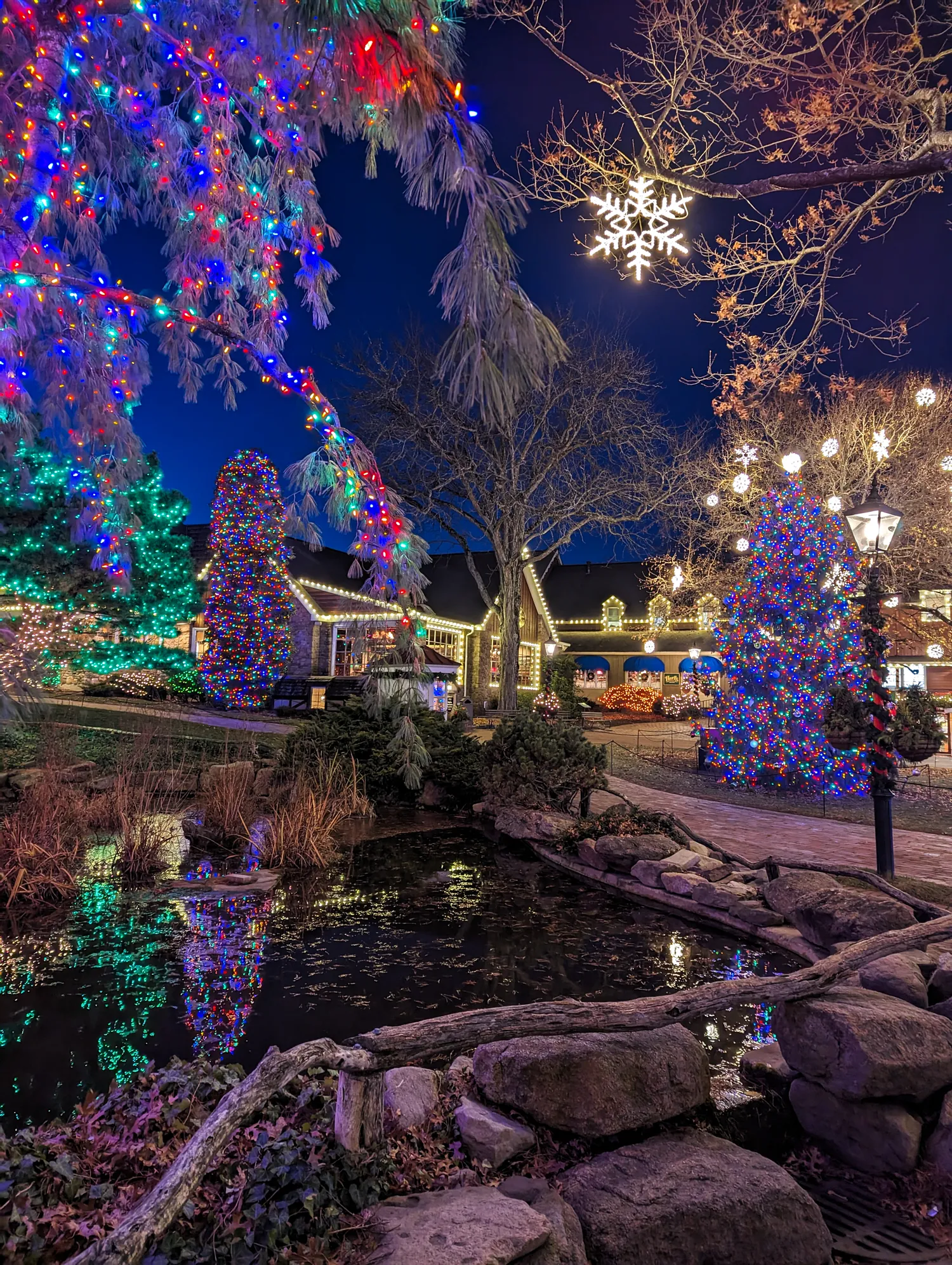 The holiday light display during dusk at Peddler's Village. Trees and buildings are glowing with lights. 