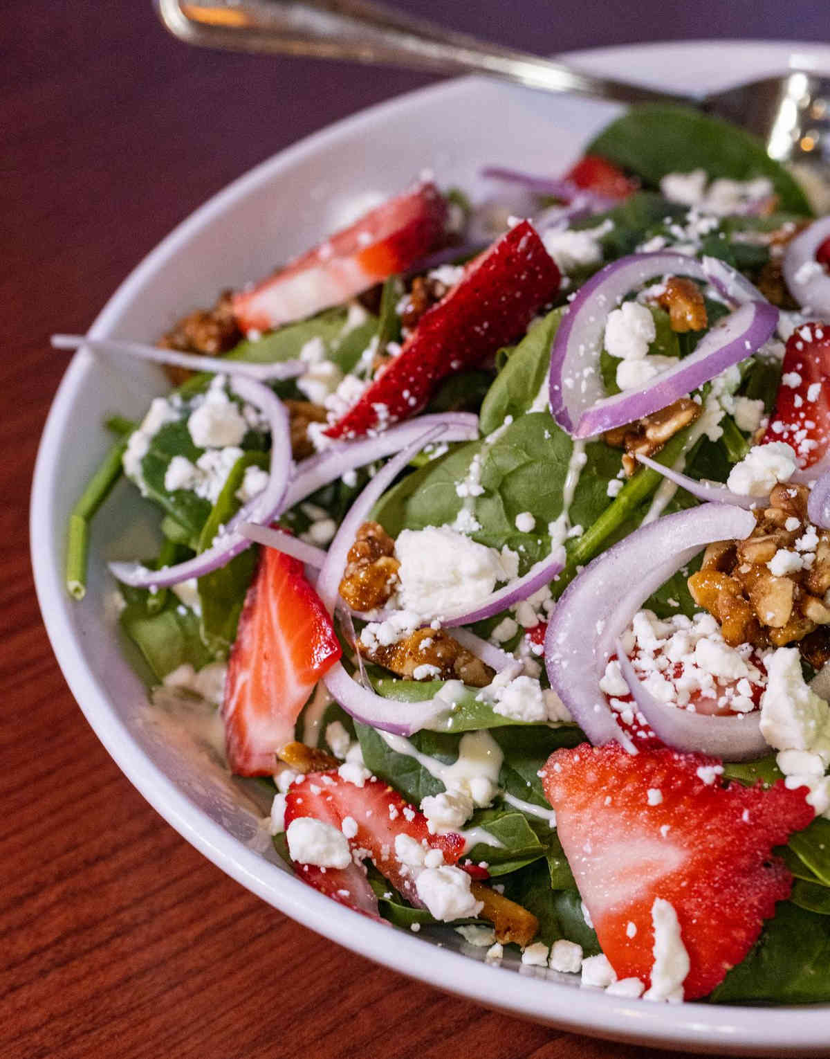 Strawberry Walnut Salad with candied walnut, red onion, cucumber, goat cheese crumble, spinach, and white balsamic vinaigrette