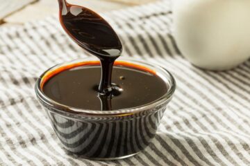 A bowl of molasses on a table with a spoon.