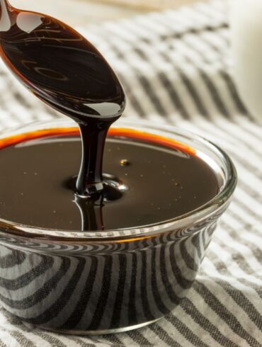 A bowl of molasses on a table with a spoon.
