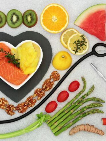 A selection of heart healthy foods on a table with a stethoscope.