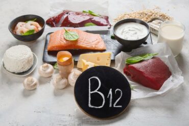 A selection of B12 rich foods on a table with a chalkboard that says B12.