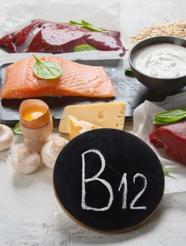 A selection of B12 rich foods on a table with a chalkboard that says B12.