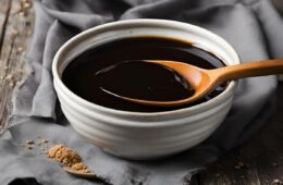 a ceramic bowl of molasses with a wooden spoon inside