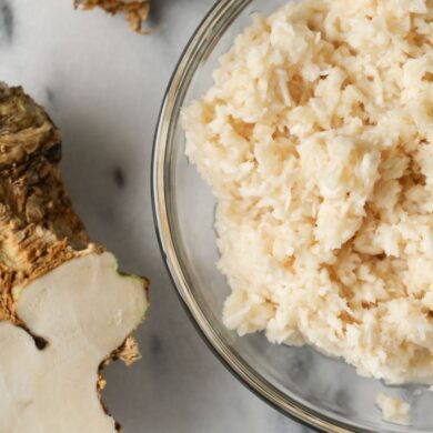 A bowl of mashed horseradish and a fresh horseradish root