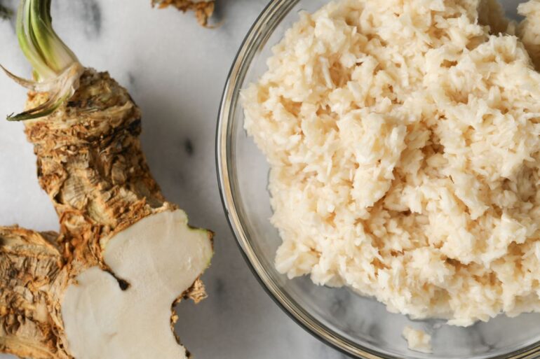 A bowl of mashed horseradish and a fresh horseradish root