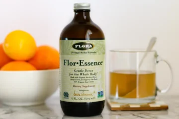 A bottle and mug of Flor-Essence herbal detox tea on a counter next to a bowl of citrus fruit.