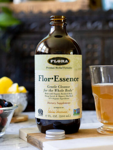 Flora For-Essence on a table with a mug of tea and fresh fruit
