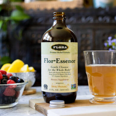 Flora For-Essence on a table with a mug of tea and fresh fruit