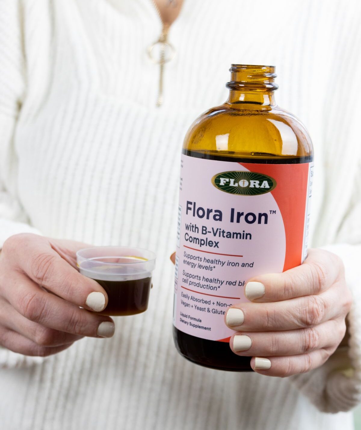 A woman holding a bottle and serving of Flora Iron