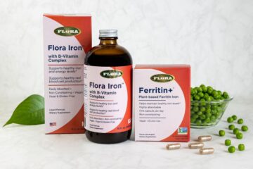 The iron supplements Ferritin+ and Flora Iron from Flora on a table with a leaf and green peas.