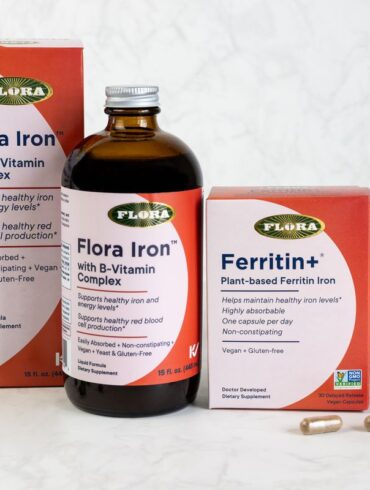 The iron supplements Ferritin+ and Flora Iron from Flora on a table with a leaf and green peas.