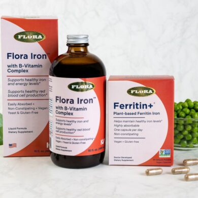 The iron supplements Ferritin+ and Flora Iron from Flora on a table with a leaf and green peas.