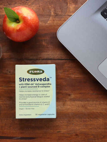 A box of Stressveda ksm-66 ashwagandha on a table with a laptop, water, and apple.