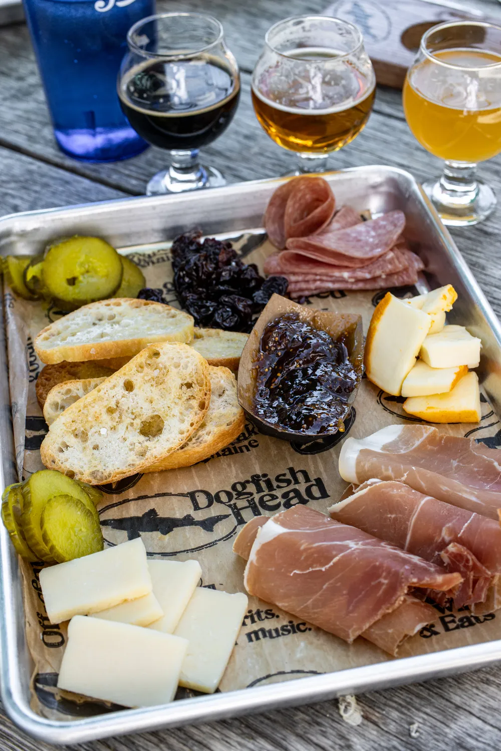 Enjoying charcuterie after our tour at Dogfish Head in Milton, DE. A plate of meats, cheeses, bread, and 3 tasting samples. 