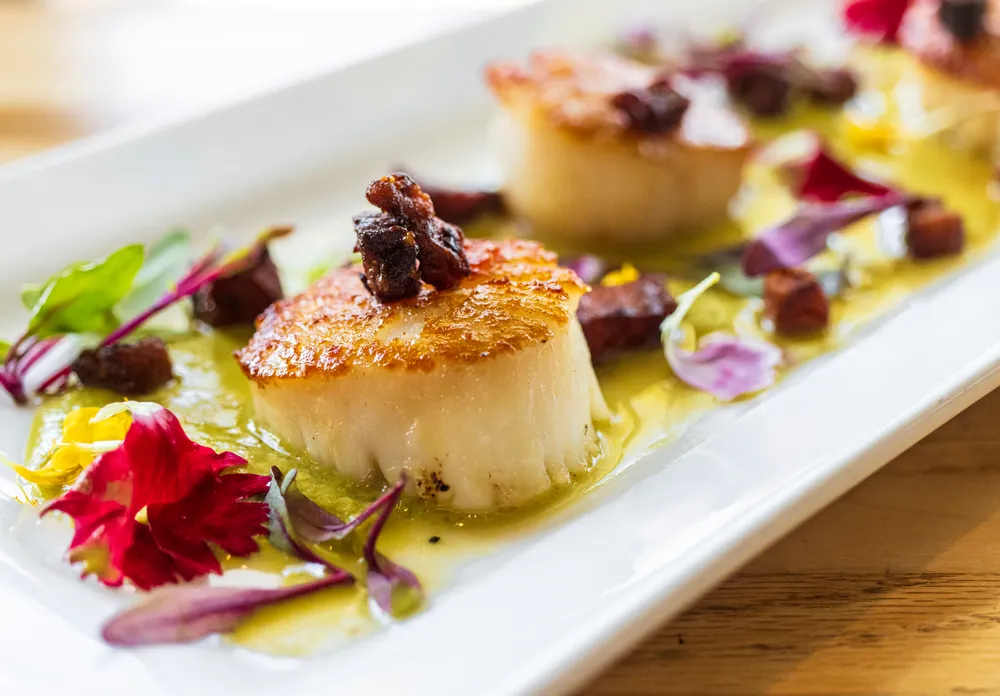Seared  Scallops at Chesapeake & Maine . 3 on a plate with edible flowers. 