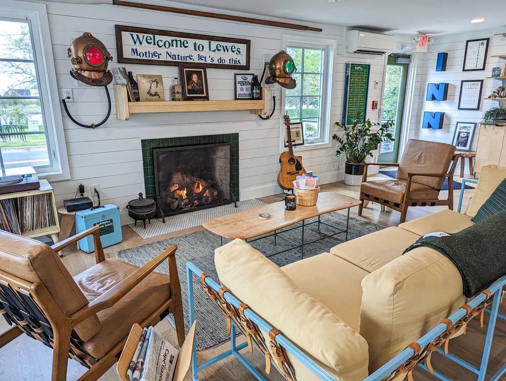 The newly updated lobby at Dogfish Inn. 2 chairs, a sofa, fireplace, guitar, book collection, and vinyl lp collection.