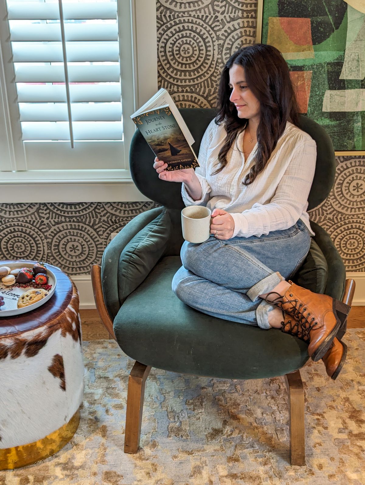 A woman reading in a chair with a cup of coffee 