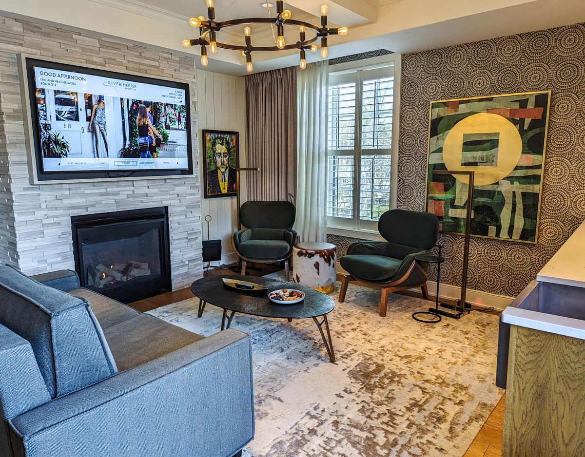 The living area of the River View King Suite at River House. A couch, chairs, fireplace, kitchenette, and tv.