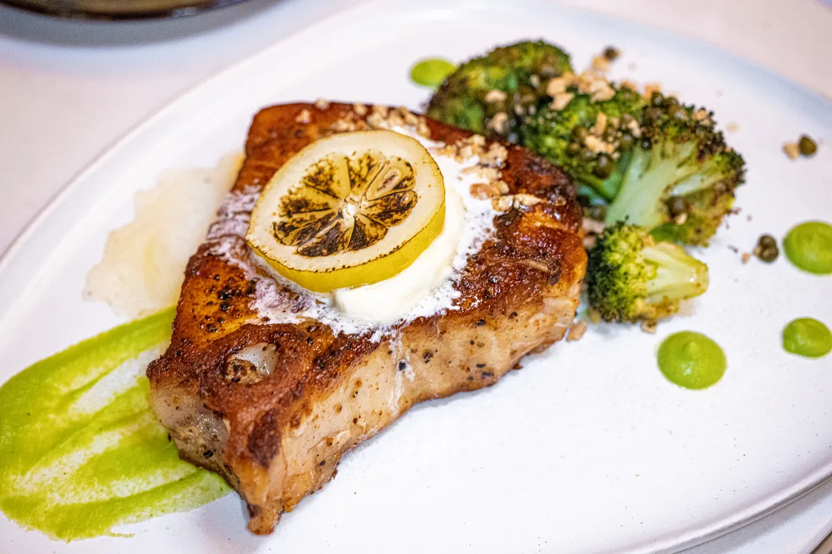 Swordfish & The Stone at Fawn & Fable. A swordfish steak with lemon, butter, and roasted broccoli on the plate. 