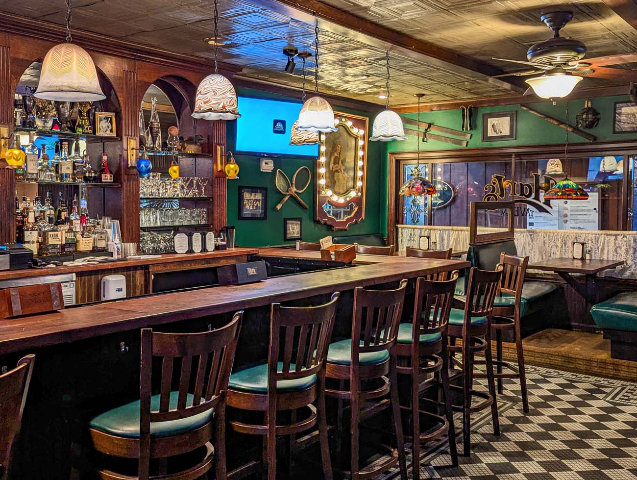 Traditional pub interior of Hart's Tavern featuring dark wood bar, green walls, nautical decor, vintage pendant lights, bar stools, and classic tavern atmosphere with multiple beer taps