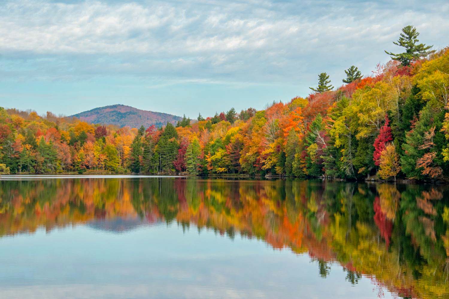 Gorgeous fall foliage reflecting in a tranquil Vermont lake, showcasing vibrant autumn colors