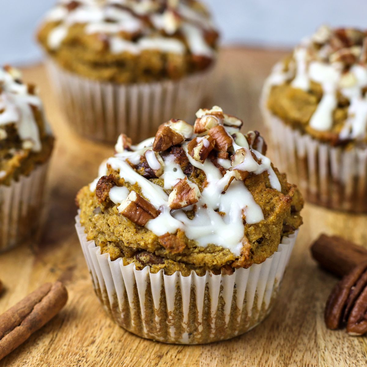 Close-up of moist pumpkin pecan muffins topped with a rich glaze and crunchy pecans. Featuring warm spices and seasonal flavors, it's ideal for fall baking.