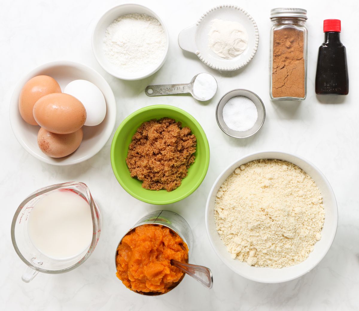 Ingredients for homemade pumpkin pecan muffins, including eggs, almond flour, canned pumpkin puree, brown sugar, spices, and pecans. Ready for creating a delicious fall-inspired treat.