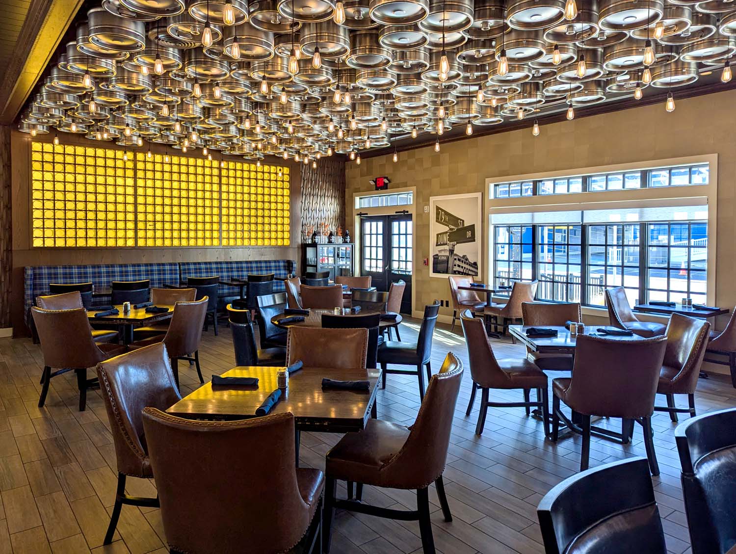 Interior of Avalon Brew Pub showing a ceiling decorated with beer kegs and Edison bulbs, leather chairs, and an illuminated yellow wall feature