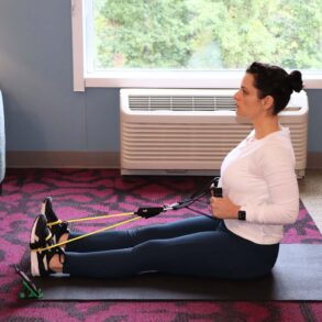 Woman performing seated resistance band rows in home or hotel setting, demonstrating Future app's flexibility for maintaining fitness routines while traveling