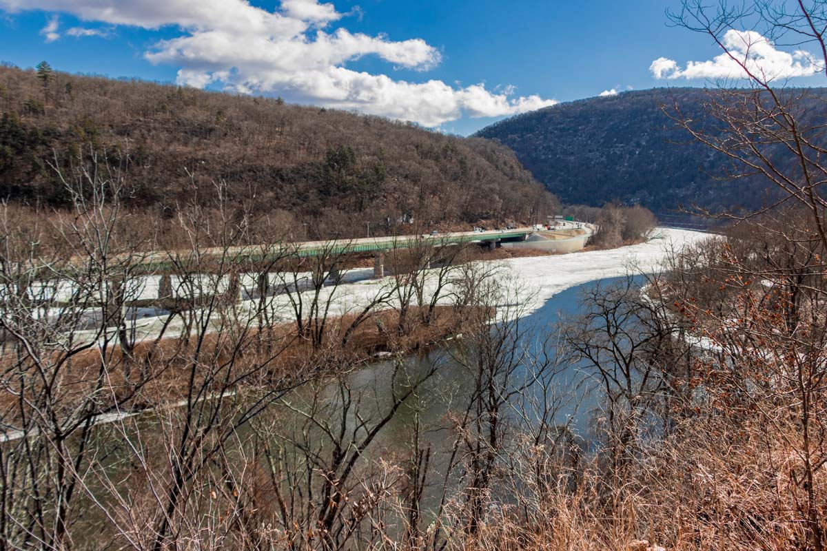 Scenic winter landscape view of a winding river and snow-covered grounds from the Delaware Water Gap. Mountains in the background.