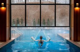 Heather from Better Living enjoying the heated indoor outdoor pool at The Swiftwater. Arching water features while snow falls outside the floor-to-ceiling windows