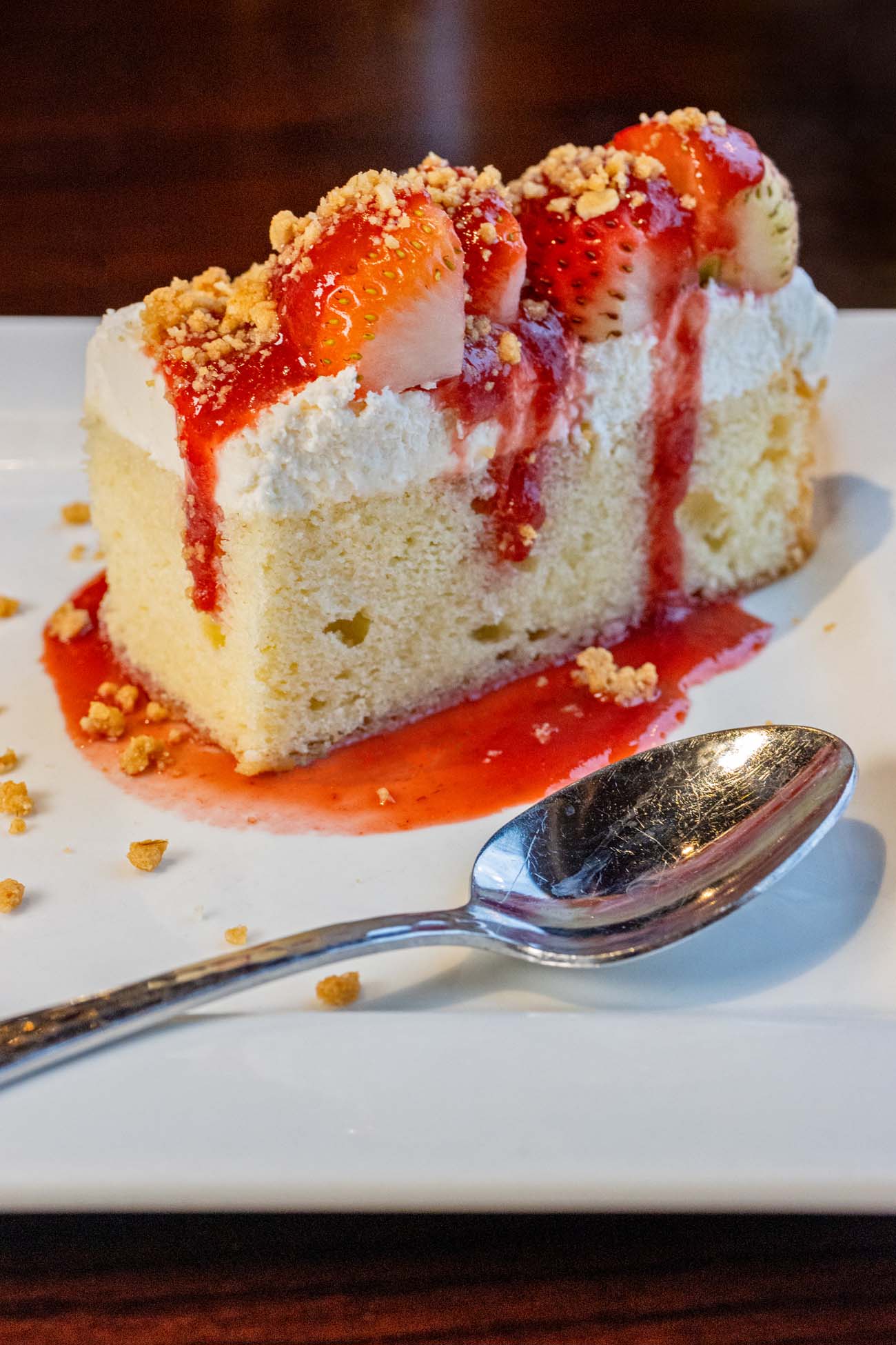 Strawberry shortcake on a square plate with a spoon at Buttonwood Grill.