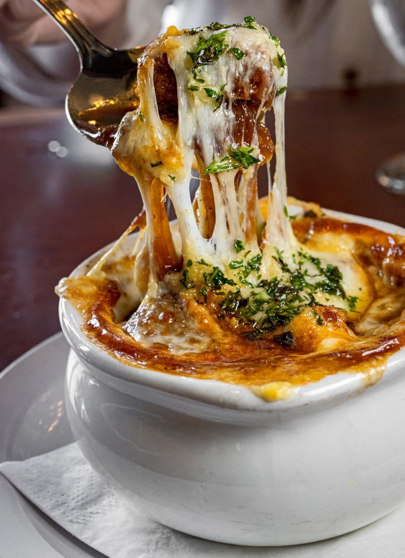 A bowl of French onion soup with an epic cheese pull at Cock N Bull.