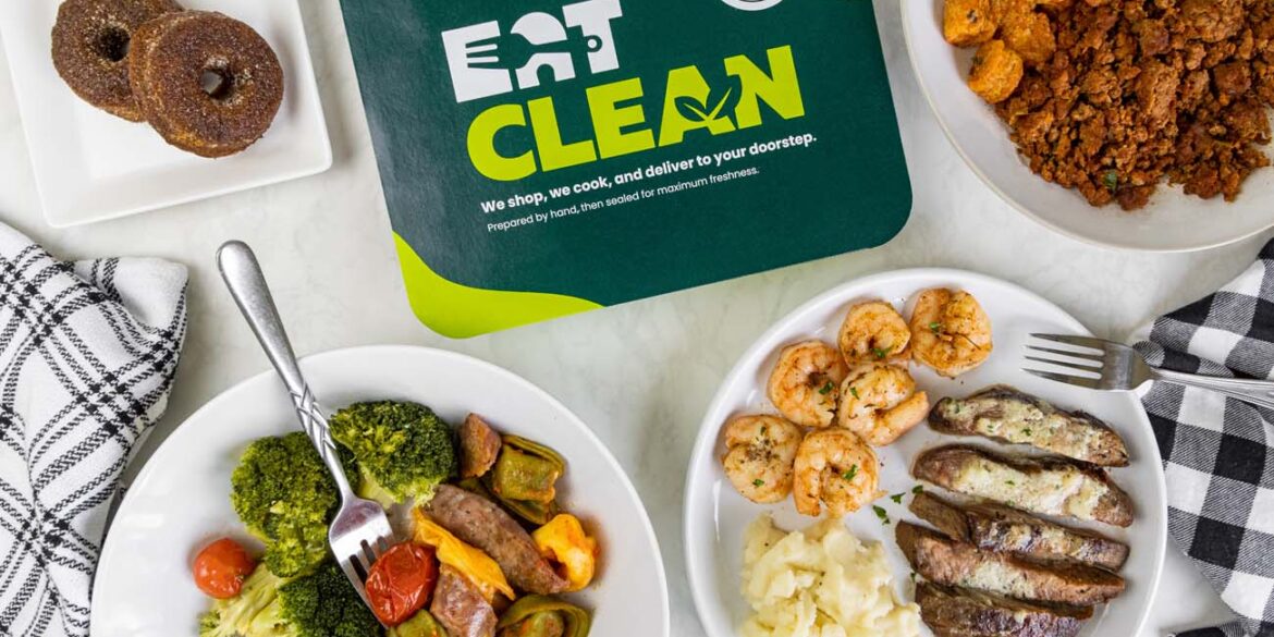Overhead view of multiple Eat Clean meals arranged on a white marble surface. Visible dishes include pulled pork, sausage with vegetables, surf and turf with potatoes, meatballs, chicken nuggets with mac and cheese, and mini churro donuts. The plates feature different protein options, sides, and colorful vegetables, demonstrating the variety available in their meal plans.