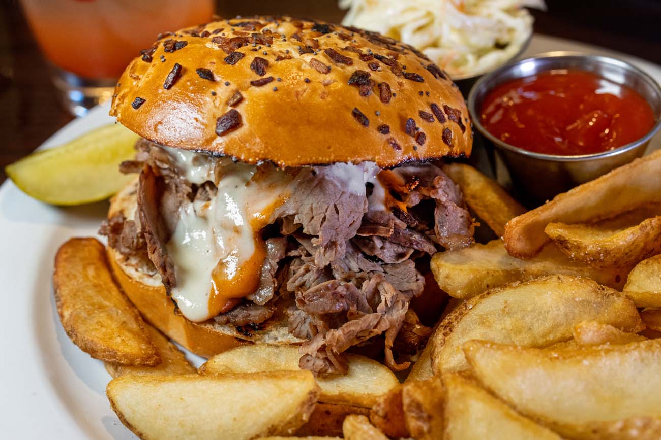 Prime rib sandwich with fries, ketchup, slaw, and a strawberry cocktail at Cock N Bull.