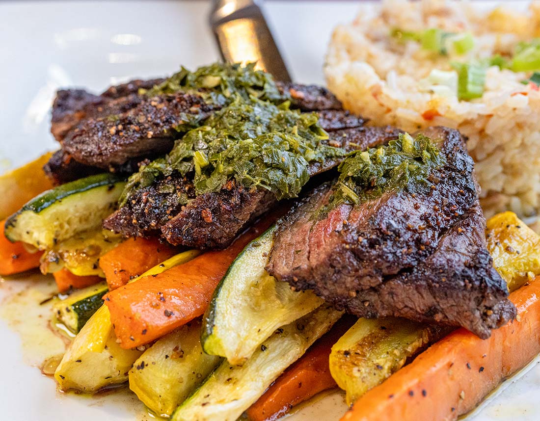 Carne Asada at Buttonwood Grill at Peddler's Village, skirt steak with chimichurri sauce, dirty rice, zucchini, yellow squash, and carrots.