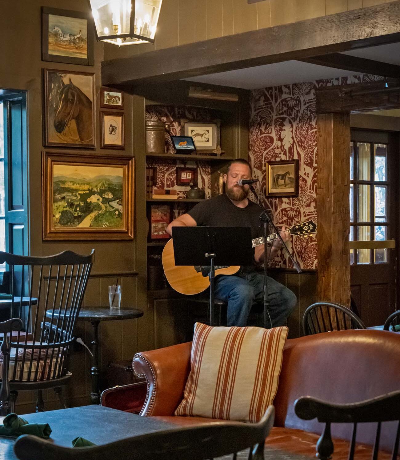 Brad Staudle performing at Red Fox Lounge. A seating area with tables and a couch.
