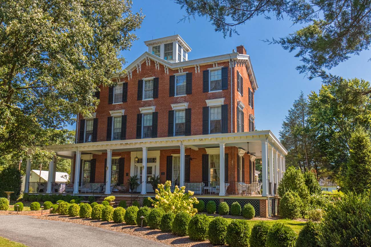 Brampton 1860 Review: A Timeless Retreat on the Eastern Shore 6 The 1860 brick Italianate Manor House at Brampton with its distinctive cupola, white columns, and wraparound porch, surrounded by manicured landscaping and mature trees.