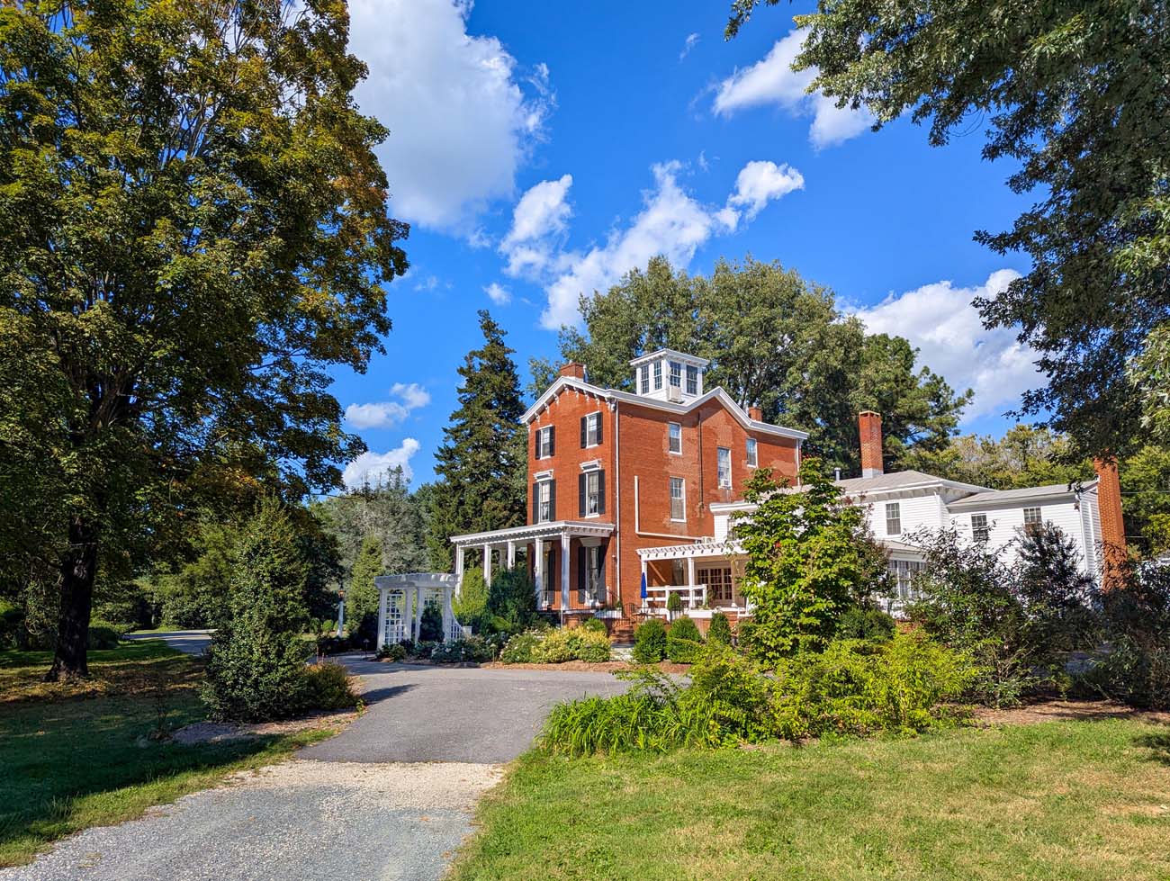 Brampton 1860 Review: A Timeless Retreat on the Eastern Shore 48 Brampton 1860's Manor House viewed from the gravel driveway approach, showing the full three-story brick facade with white trim and the property's pastoral setting.