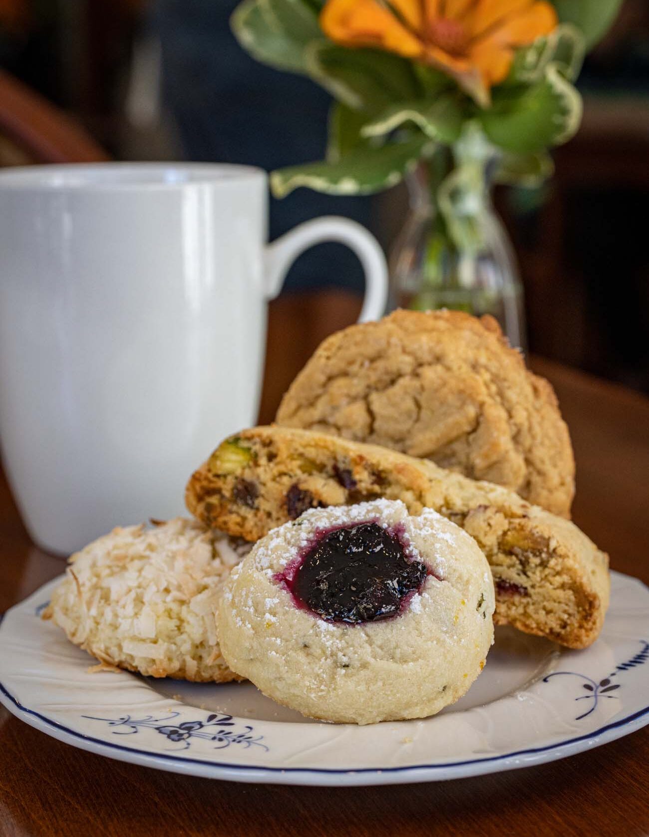 Brampton 1860 Review: A Timeless Retreat on the Eastern Shore 24 An assortment of fresh-baked tea time pastries including scones, muffins, and Danish on a Brampton-branded plate, with coffee cup and small flower arrangement.