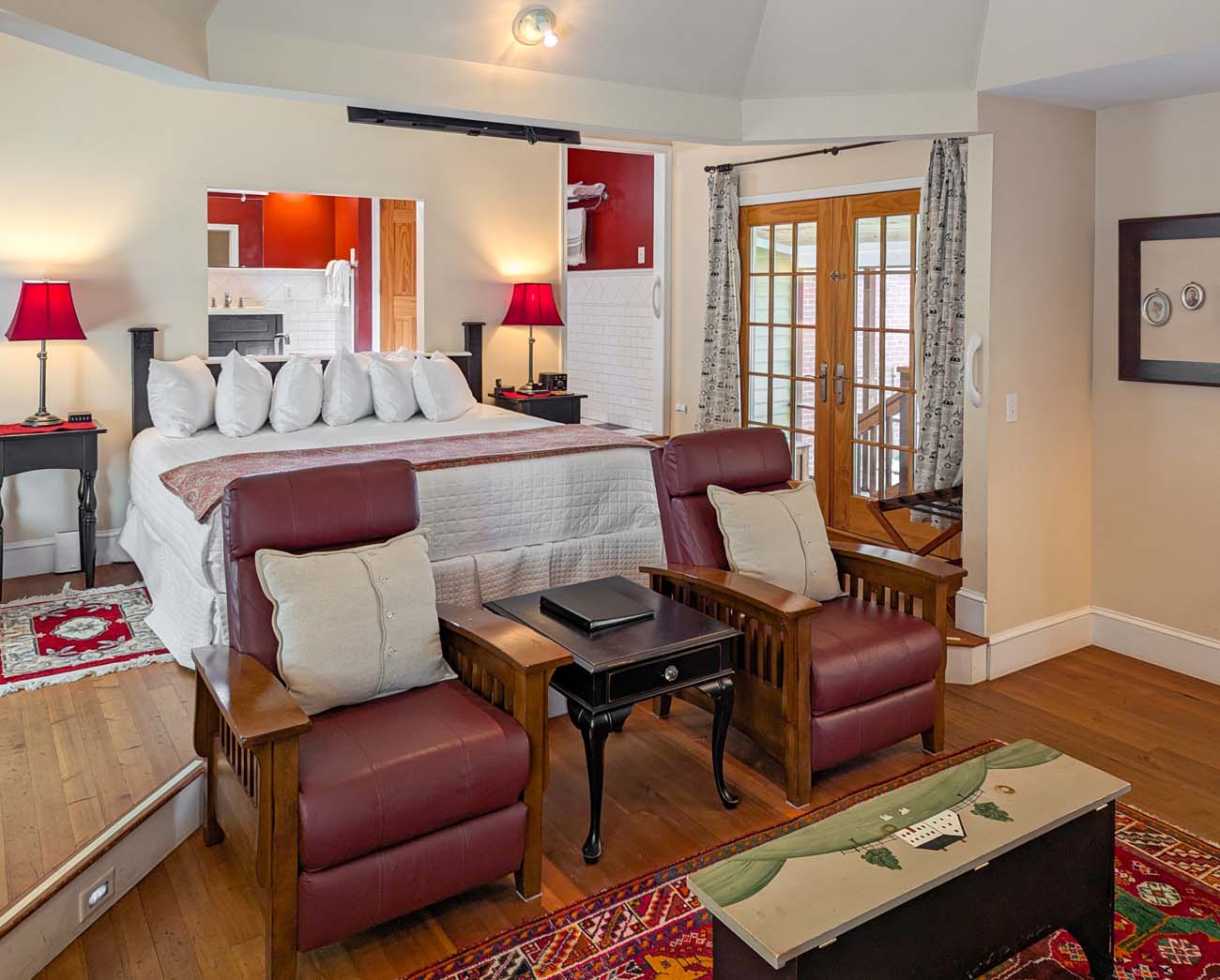 Brampton 1860 Review: A Timeless Retreat on the Eastern Shore 2 Inside Marleys Cottage at Brampton 1860 with king bed, cozy furnishings, red accent wall, fireplace, and French doors opening to a private patio