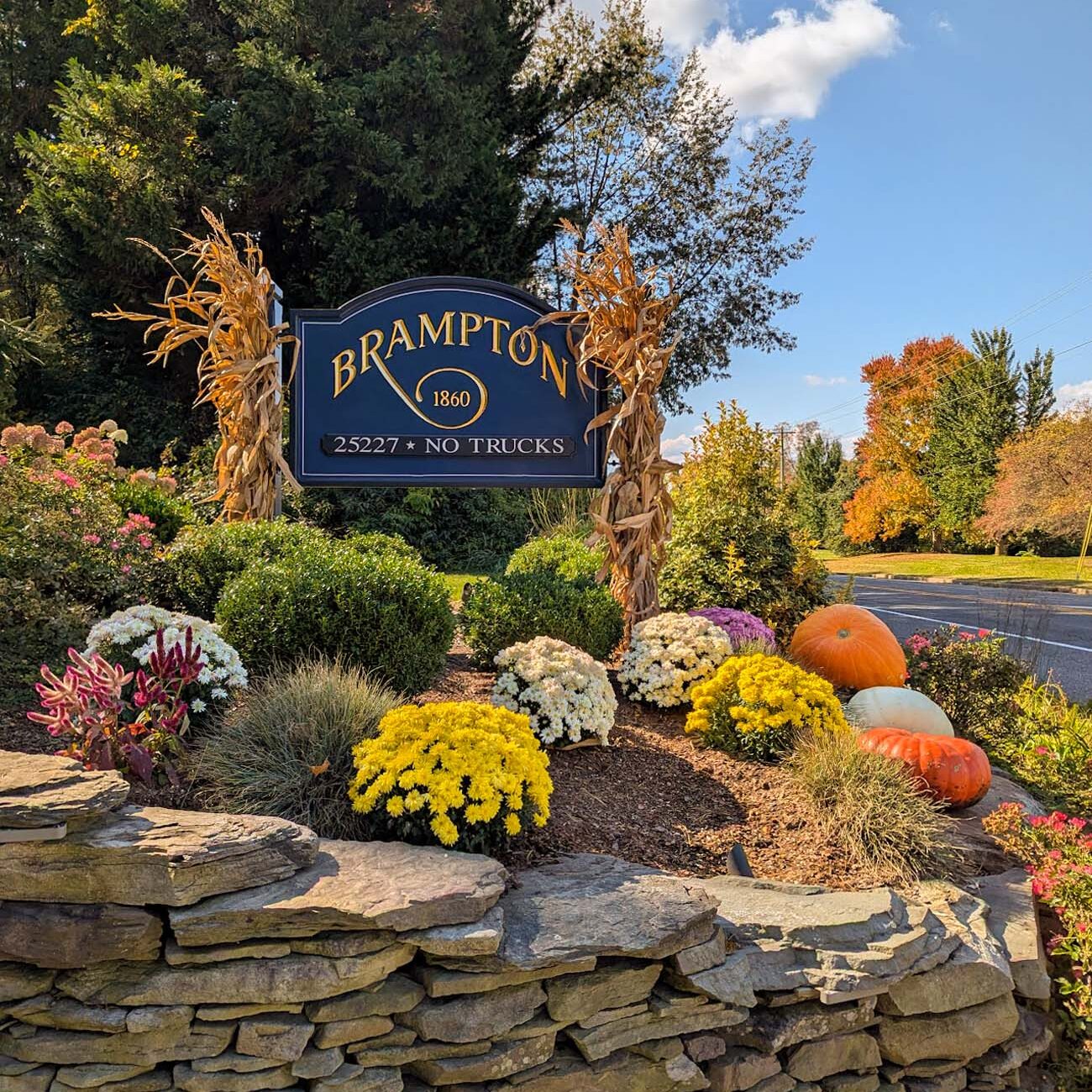 Food, Wine, and Fall Fun at Brampton 1860 - Chestertown, MD 4 Brampton 1860 blue and gold entrance sign decorated with dried corn stalks, surrounded by chrysanthemums, pumpkins, and ornamental grasses on stone wall