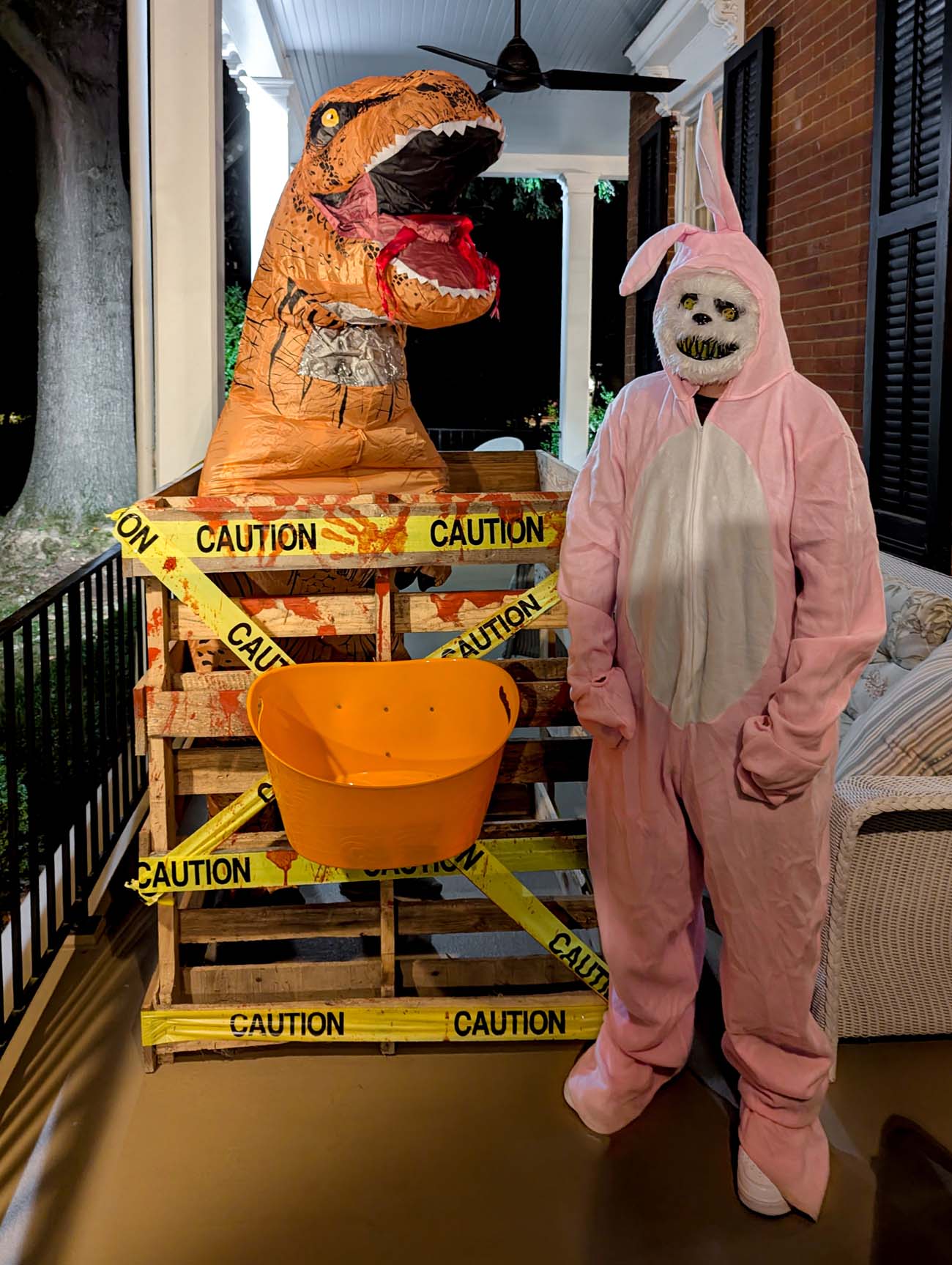 Food, Wine, and Fall Fun at Brampton 1860 - Chestertown, MD 34 Inflatable T-Rex costume and person in pink bunny onesie with scary face standing on porch with orange candy bucket and caution tape decoration