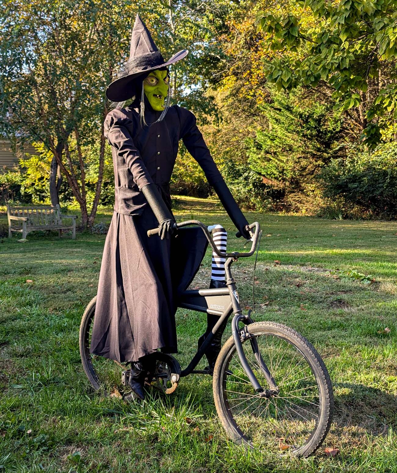 Food, Wine, and Fall Fun at Brampton 1860 - Chestertown, MD 20 Life-size witch figure with green face and black robes positioned on vintage bicycle on lawn with fall trees in background