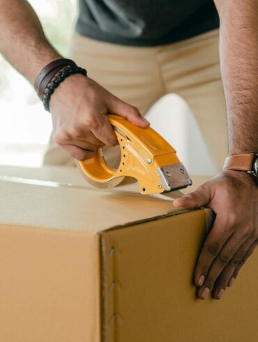 A man packing a box and taping for the Long-Distance Moving Guide What to Expect & Expert Tips