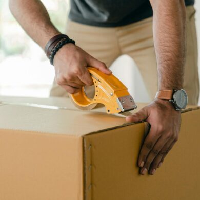 A man packing a box and taping for the Long-Distance Moving Guide What to Expect & Expert Tips