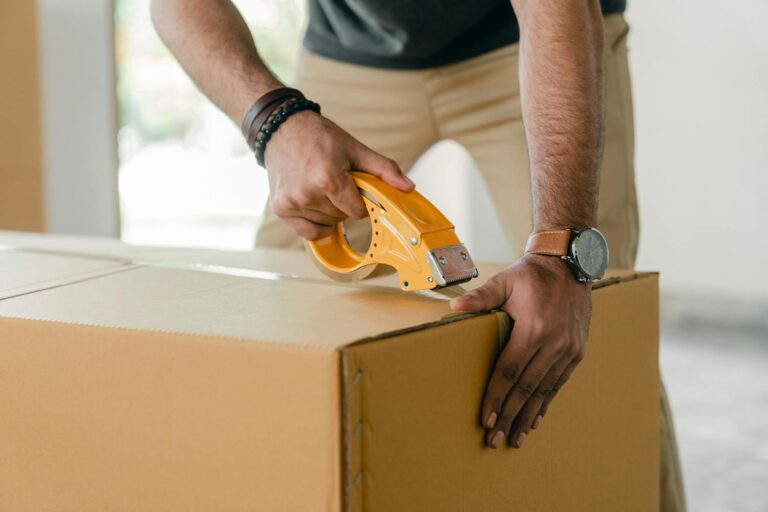 A man packing a box and taping for the Long-Distance Moving Guide What to Expect & Expert Tips